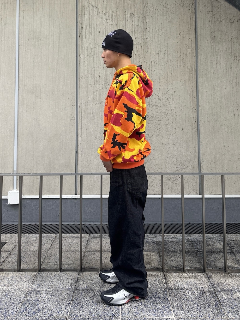 オレンジ系のパーカー、ブラック系のデニムパンツを着用したメンズの冬コーディネートの2枚目の写真