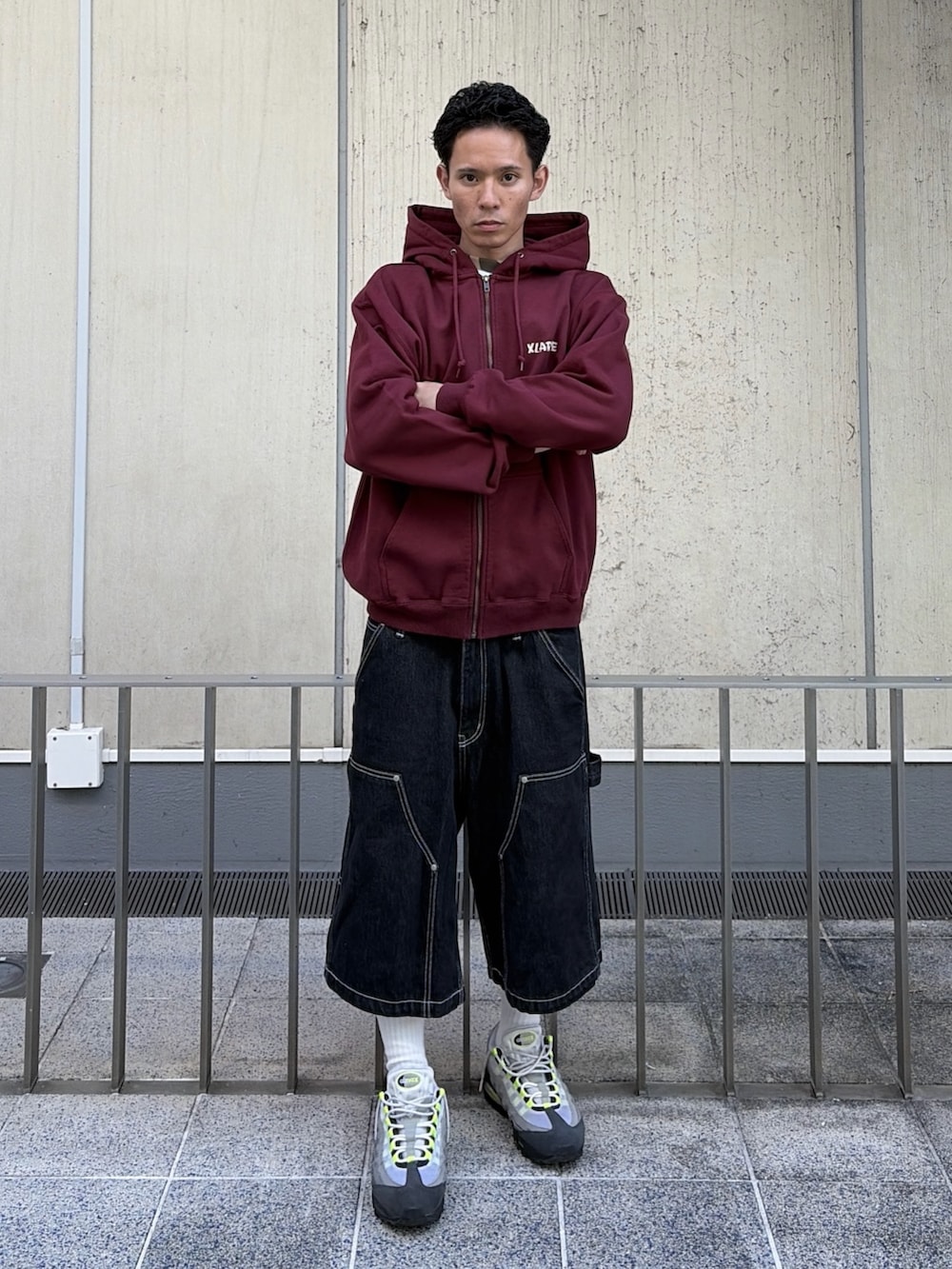 レッド系のパーカー、ブラック系のデニムパンツを着用したメンズの秋コーディネートの9枚目の写真