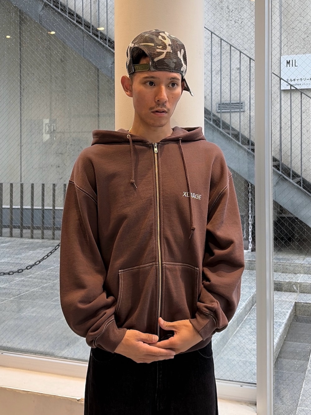 ブラウン系のパーカー、ブルー系のデニムパンツ、ブラック系のキャップを着用したメンズの秋コーディネートの6枚目の写真