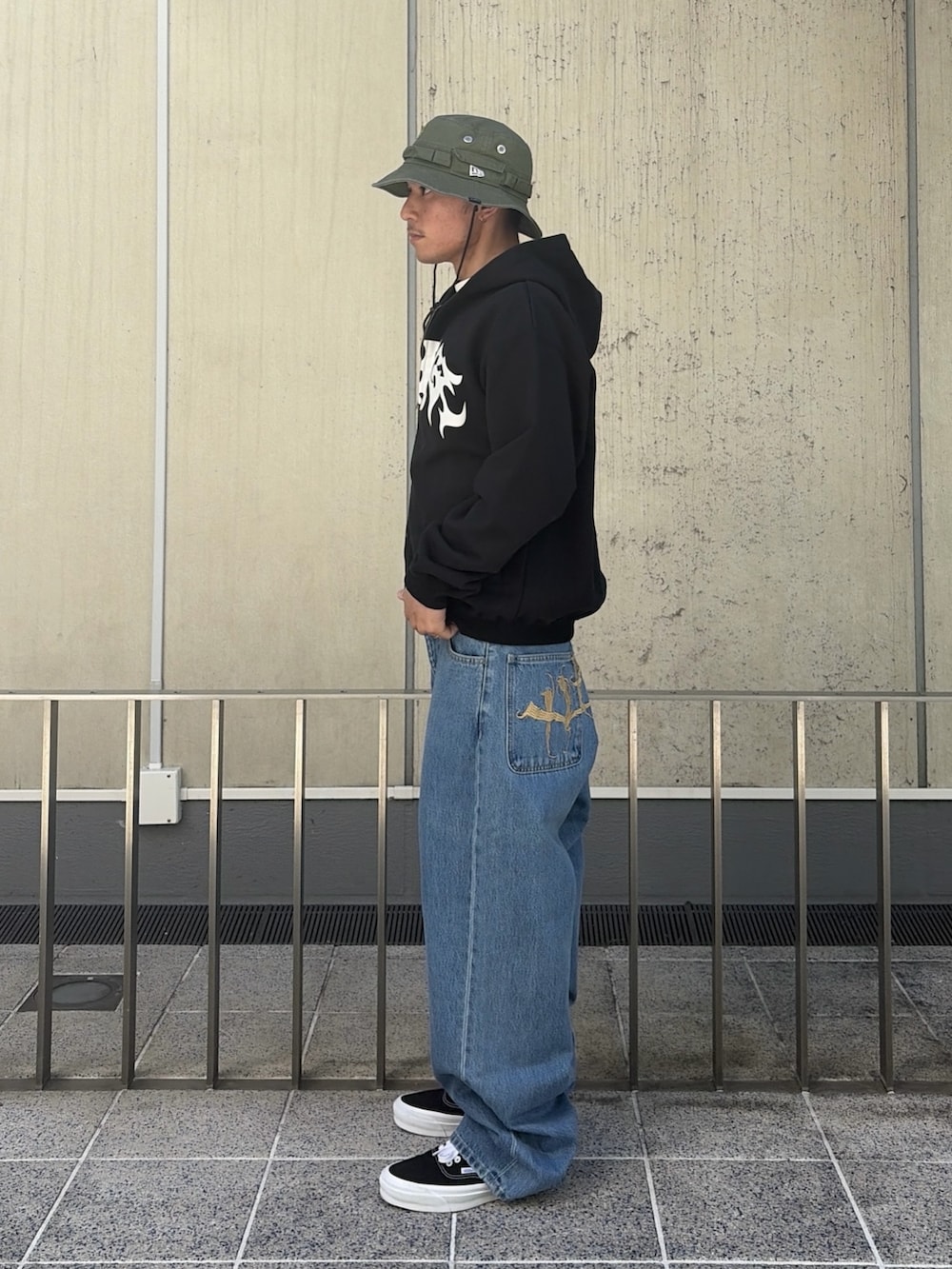 ピンク系のパーカー、ブルー系のデニムパンツ、ブラック系のハットを着用したメンズの春コーディネートの2枚目の写真