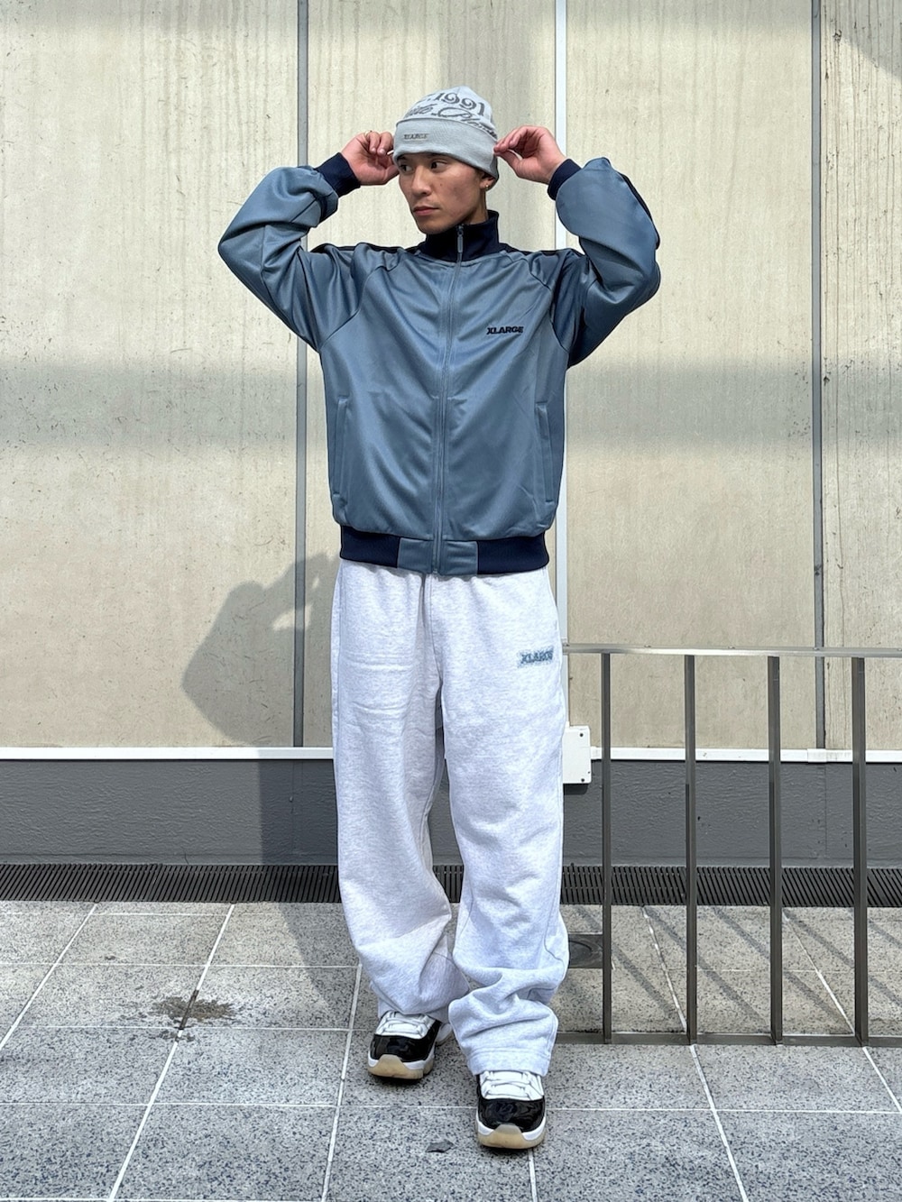 グレー系のスウェットパンツ、ブルー系のブルゾン、ブラック系のニットキャップ/ビーニーを着用したメンズの秋コーディネートの2枚目の写真