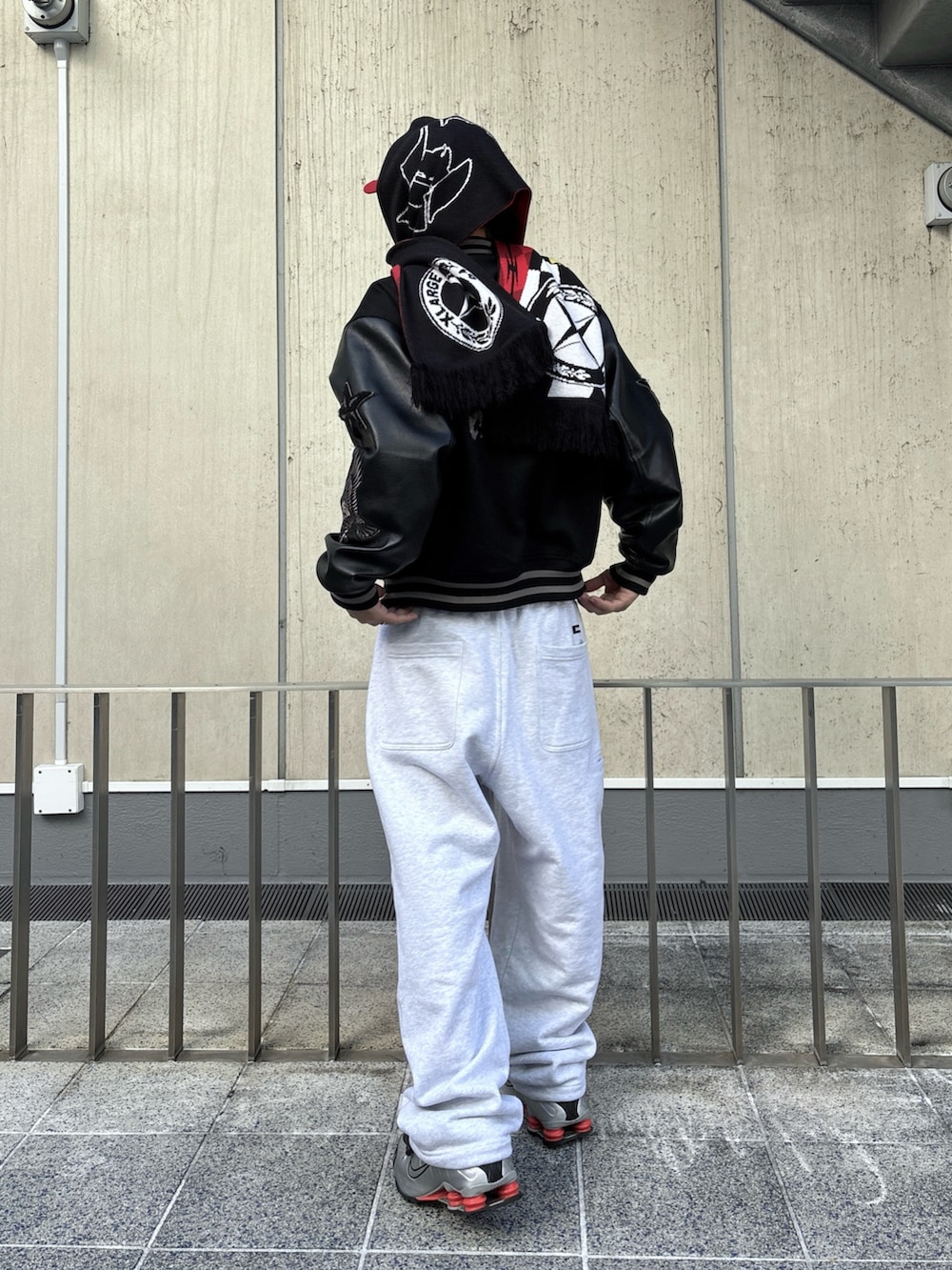 ブラック系のスタジャン、グレー系のスウェットパンツ、レッド系のキャップを着用したメンズの秋コーディネートの3枚目の写真