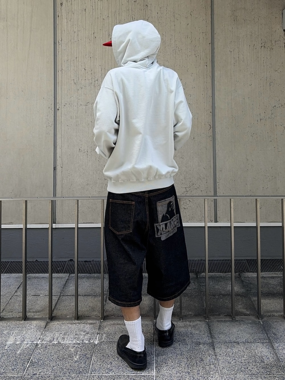 グレー系のパーカー、グリーン系のデニムパンツ、レッド系のキャップを着用したメンズの夏コーディネートの5枚目の写真