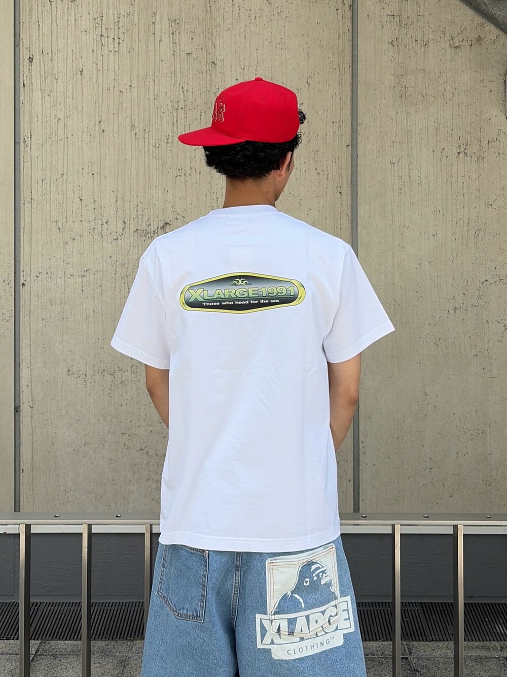 グリーン系のデニムパンツ、ホワイト系のTシャツ/カットソー、レッド系のキャップを着用したメンズの春コーディネートの6枚目の写真
