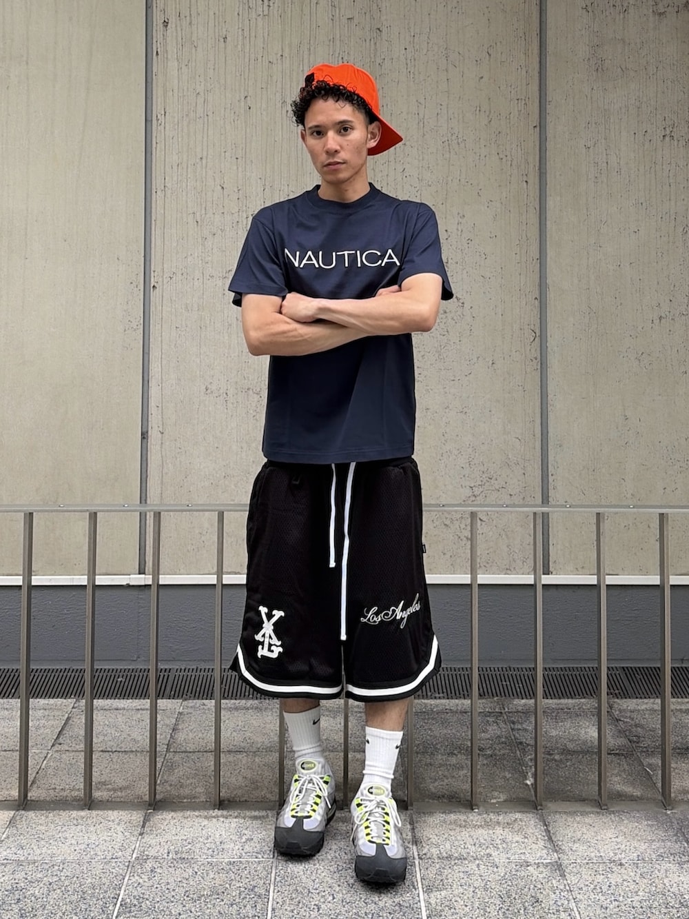 ブラック系のその他パンツ、ブルー系のTシャツ/カットソー、オレンジ系のキャップを着用したメンズの夏コーディネートの2枚目の写真