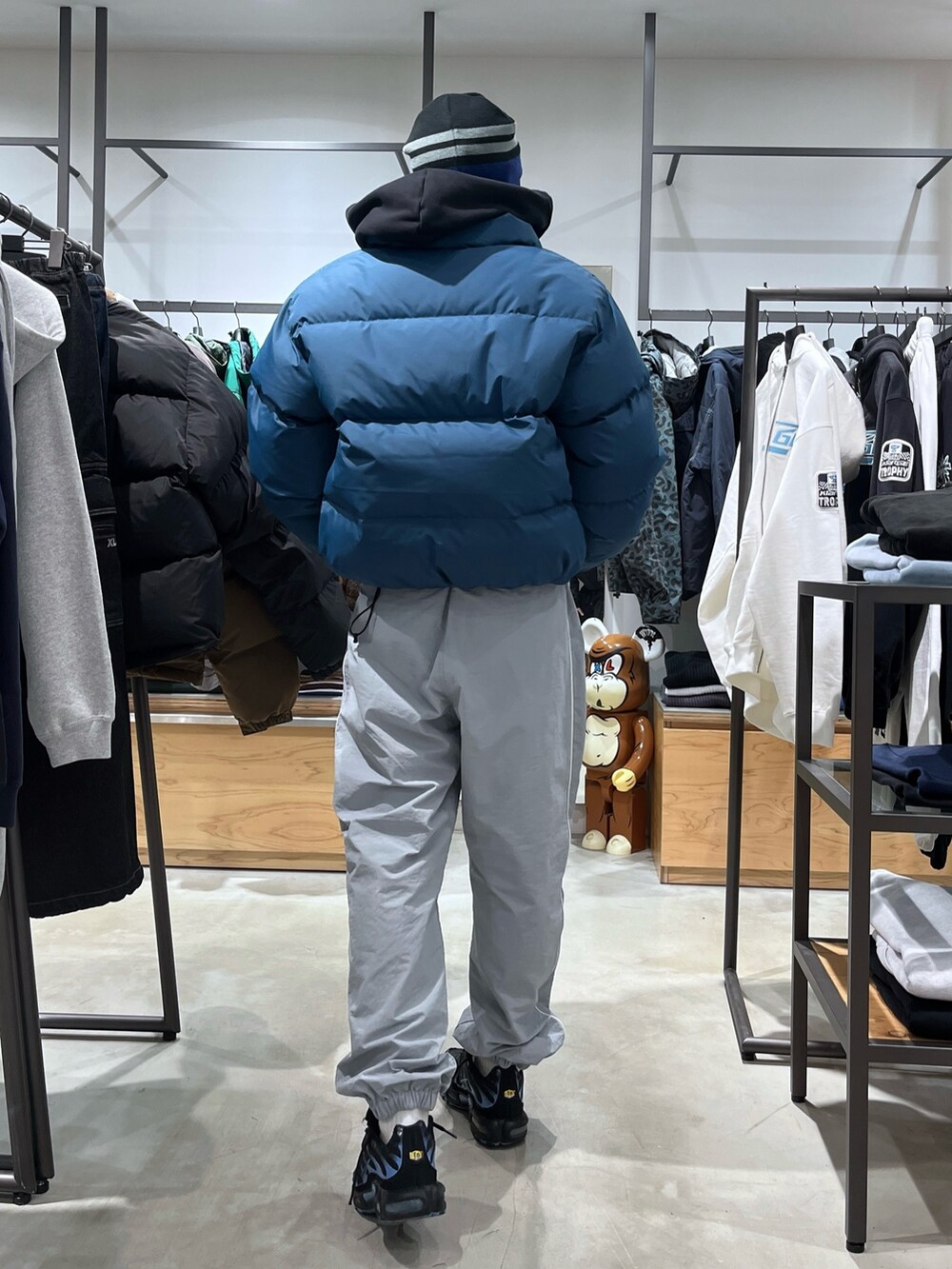 ブルー系のダウンジャケット/コート、グレー系のその他パンツ、ブラック系のニットキャップ/ビーニーを着用したメンズの秋コーディネートの5枚目の写真