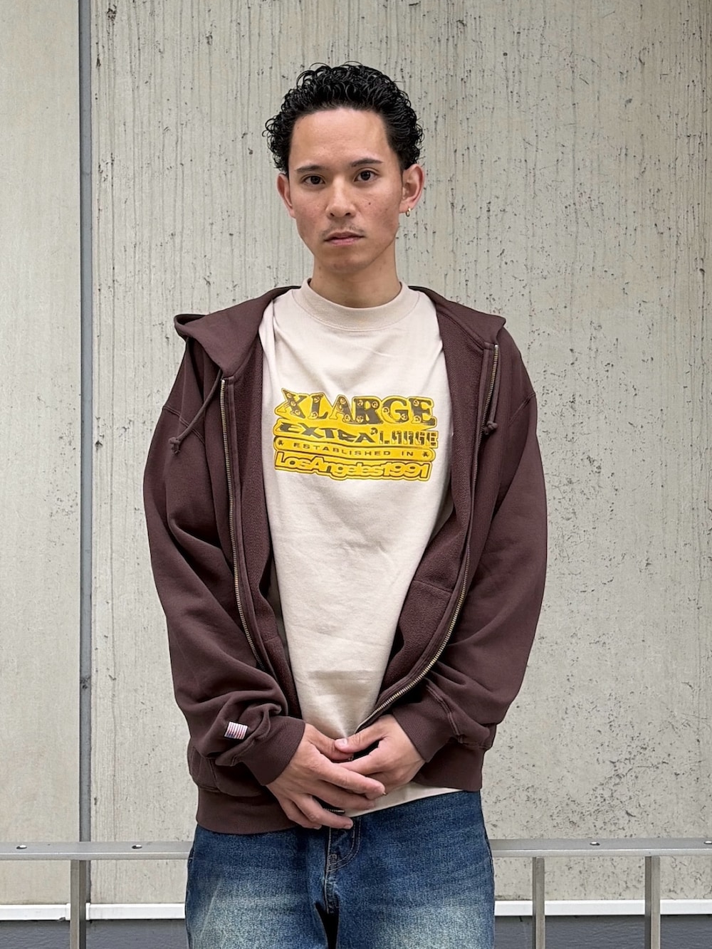 ベージュ系のTシャツ/カットソー、ブラウン系のパーカー、ブルー系のデニムパンツを着用したメンズの春コーディネートの5枚目の写真