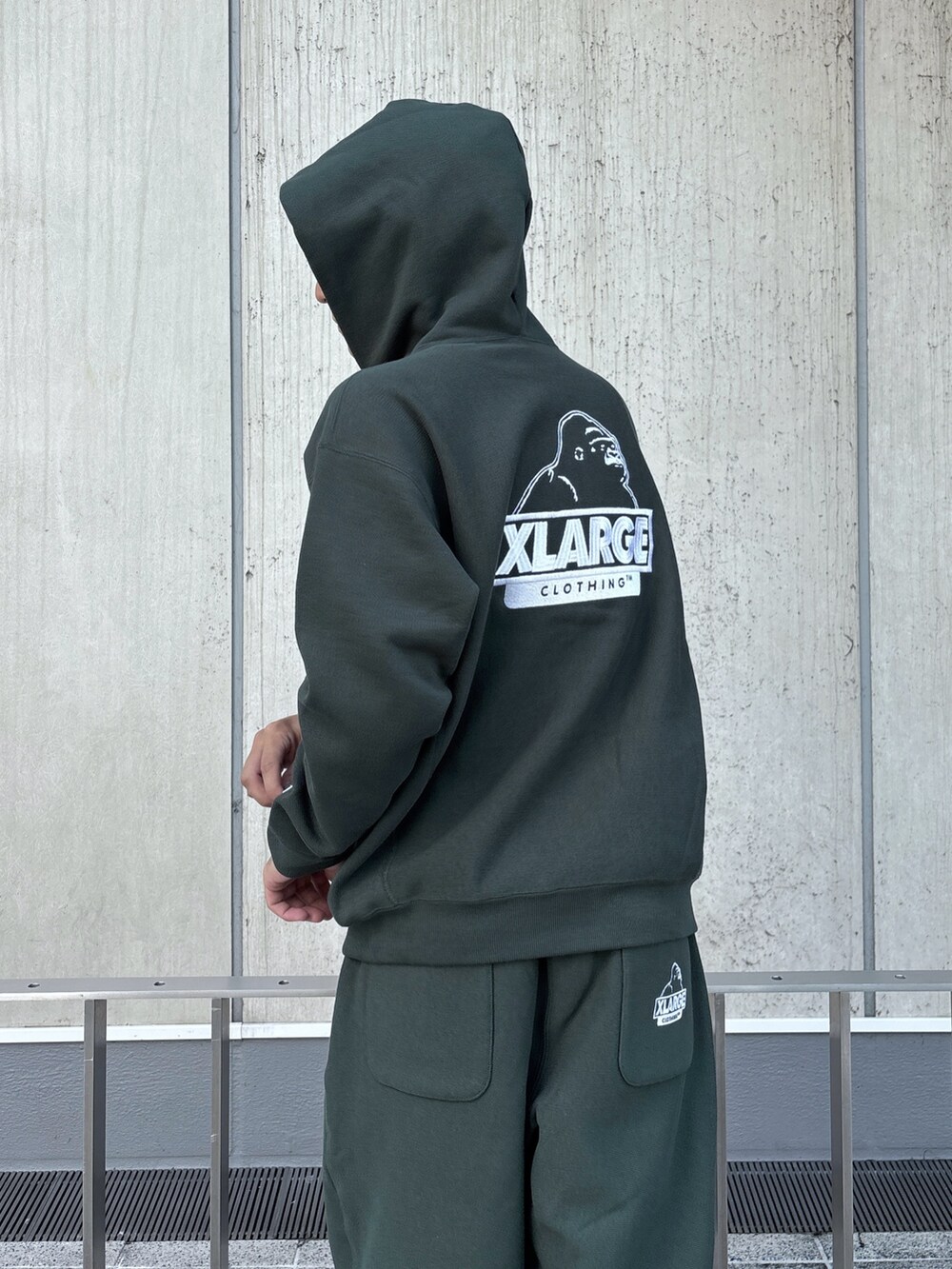 グリーン系のパーカー、グリーン系のスウェットパンツ、ブラック系のキャップを着用したメンズの秋コーディネートの7枚目の写真