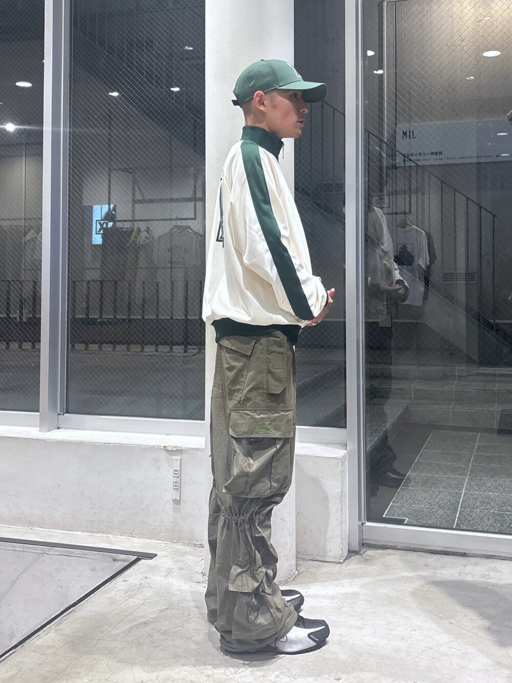 ホワイト系のブルゾン、グリーン系のカーゴパンツ、グリーン系のキャップを着用したメンズの秋コーディネートの3枚目の写真