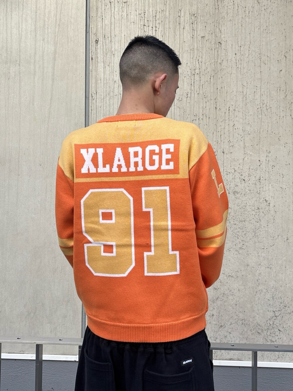 オレンジ系のニット/セーター、グレー系のスウェットパンツを着用したメンズの冬コーディネートの6枚目の写真