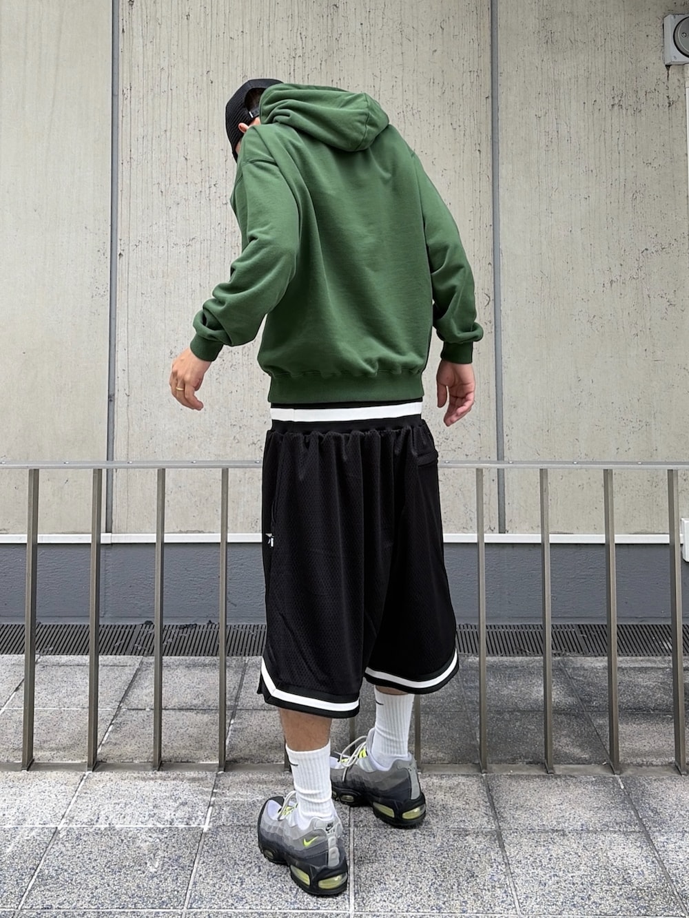 グリーン系のパーカー、ブラック系のその他パンツ、ブラック系のキャップを着用したメンズの夏コーディネートの4枚目の写真