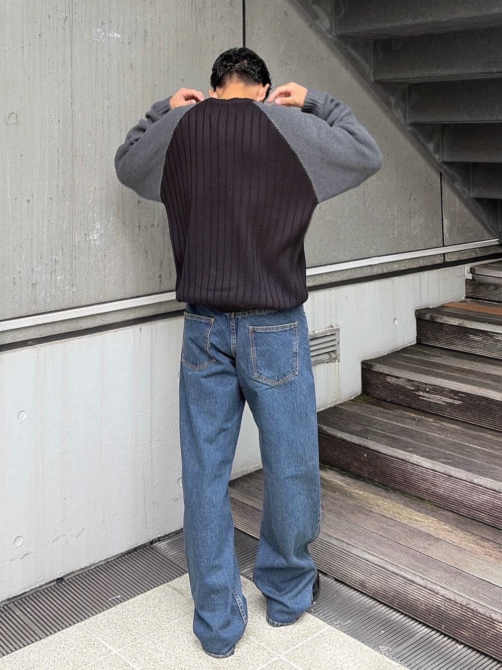 ブラック系のニット/セーター、ブルー系のデニムパンツを着用したメンズの秋コーディネートの4枚目の写真