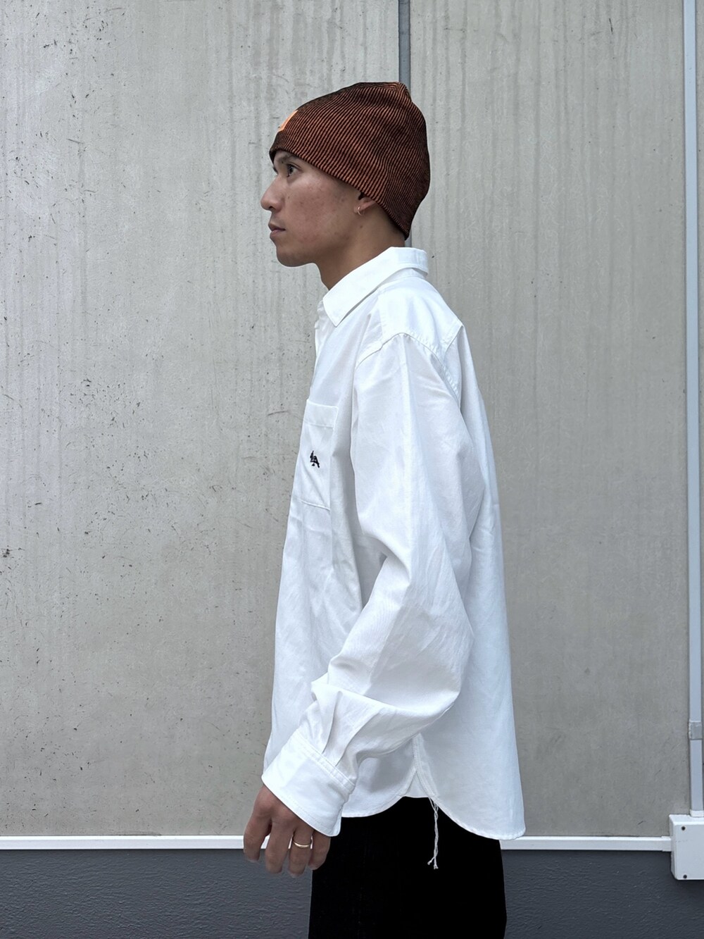 ホワイト系のシャツ/ブラウス、ブラック系のデニムパンツ、オレンジ系のニットキャップ/ビーニーを着用したメンズの秋コーディネートの6枚目の写真