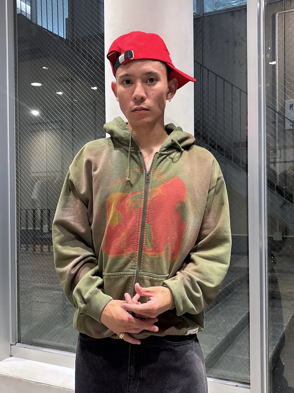 ブラック系のデニムジャケット、グリーン系のパーカー、ブラウン系のデニムパンツを着用したメンズの秋コーディネートの6枚目の写真