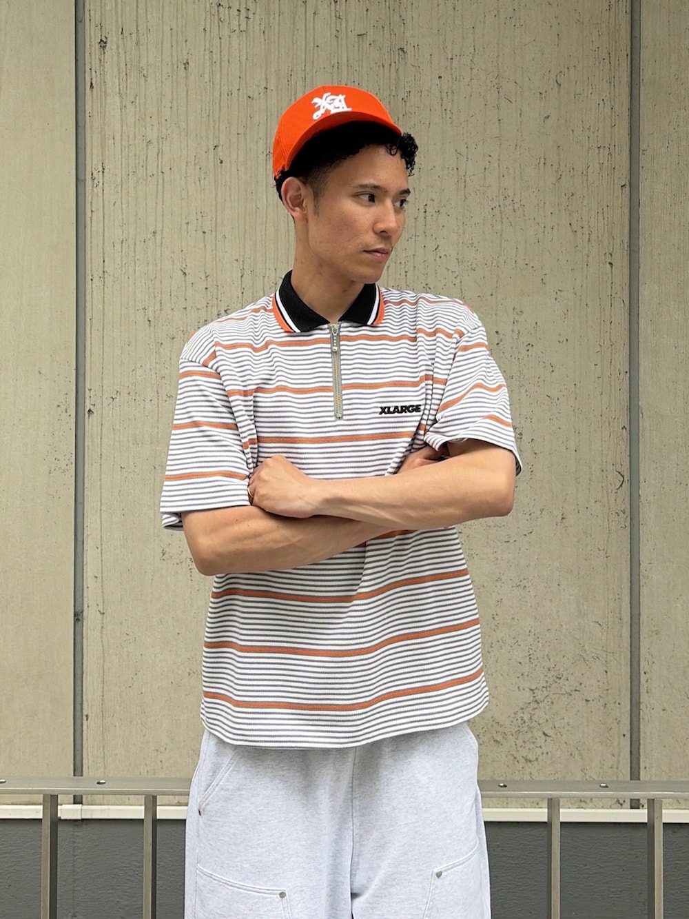 グレー系のスウェットパンツ、グレー系のTシャツ/カットソー、オレンジ系のキャップを着用したメンズの夏コーディネートの6枚目の写真