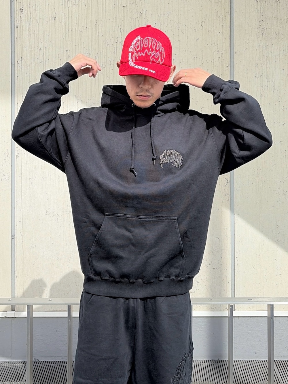 ブラック系のパーカー、ブラック系のその他パンツ、レッド系のキャップを着用したメンズの夏コーディネートの7枚目の写真