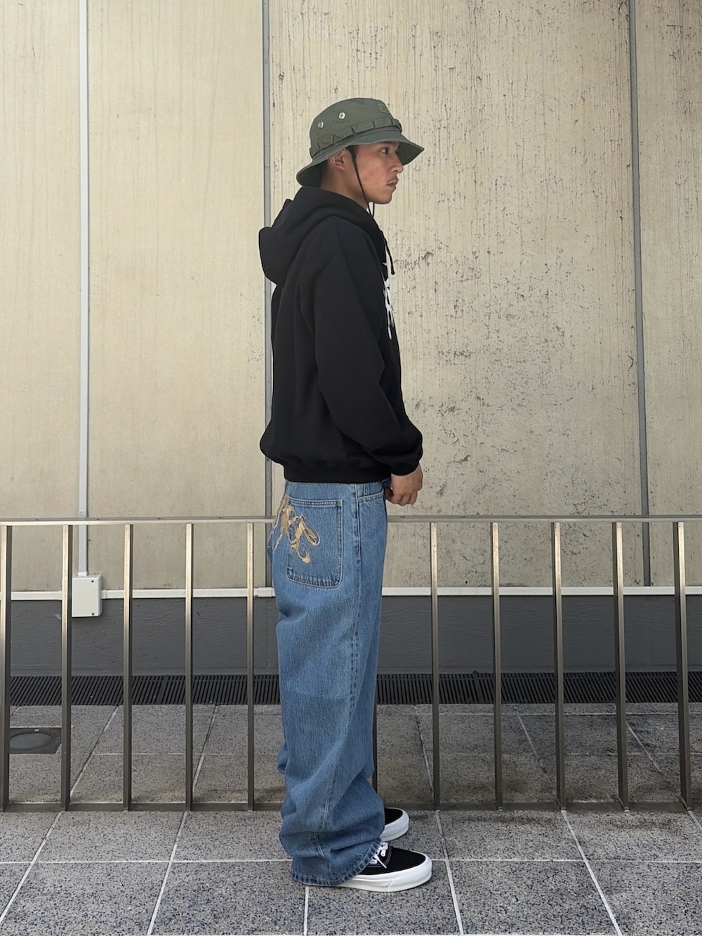 ピンク系のパーカー、ブルー系のデニムパンツ、ブラック系のハットを着用したメンズの春コーディネートの3枚目の写真