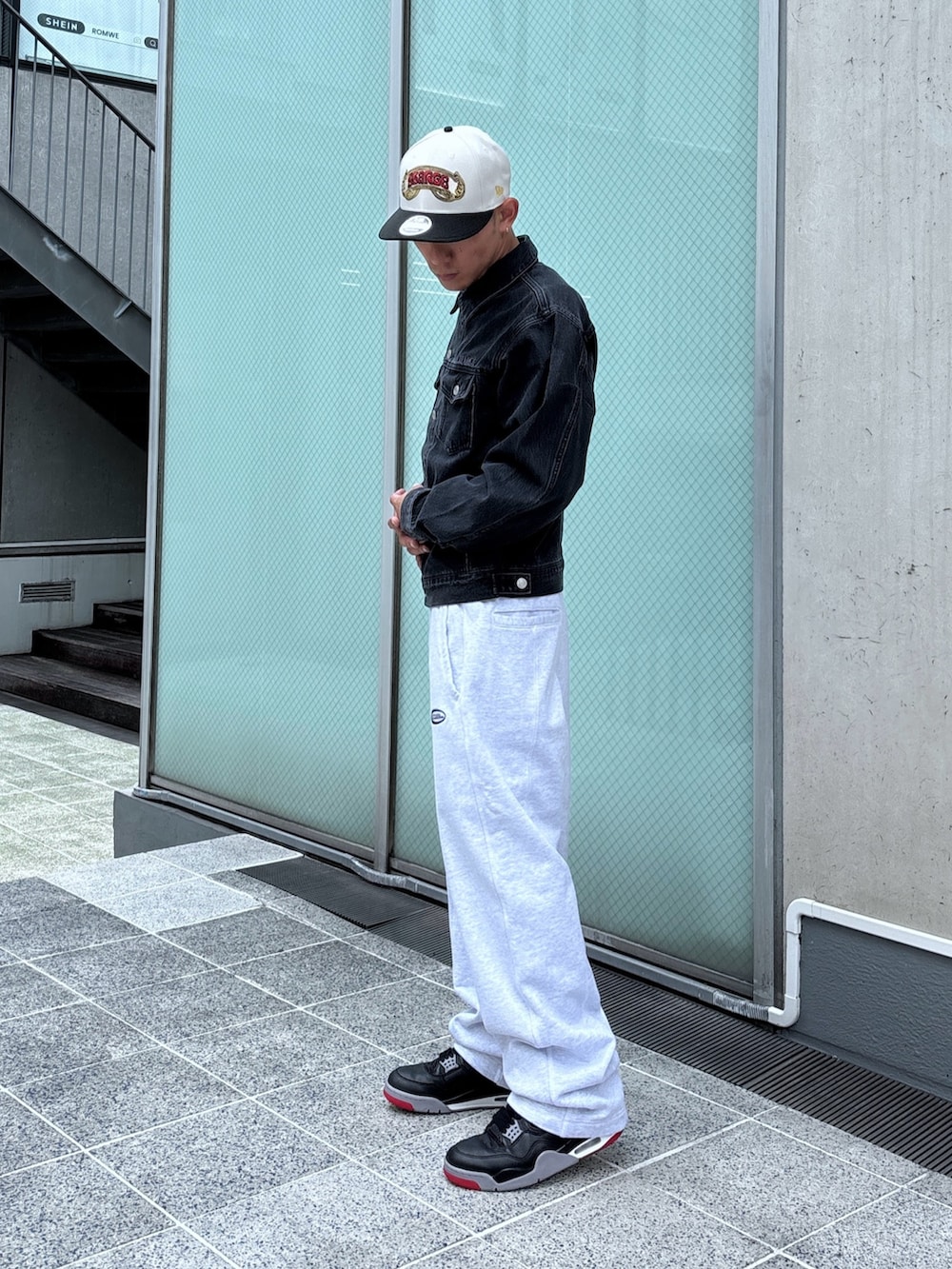 ブラック系のデニムジャケット、グレー系のスウェットパンツ、ホワイト系のキャップを着用したメンズの秋コーディネートの3枚目の写真