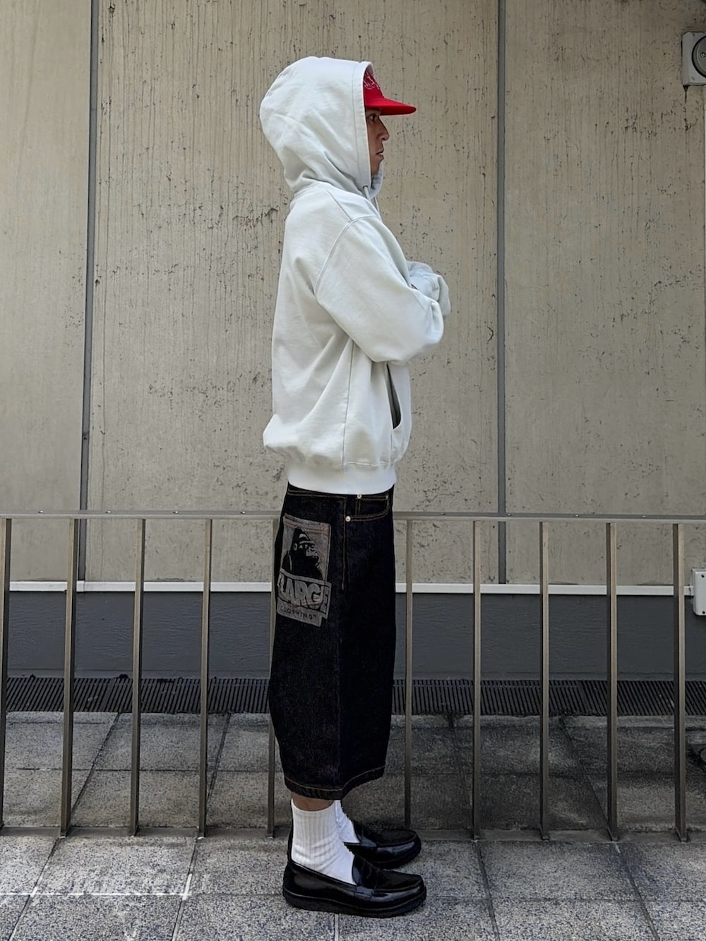 グレー系のパーカー、グリーン系のデニムパンツ、レッド系のキャップを着用したメンズの夏コーディネートの4枚目の写真