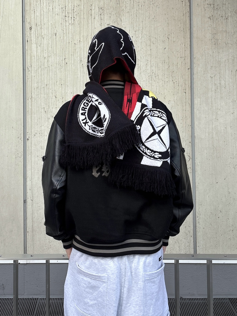 ブラック系のスタジャン、グレー系のスウェットパンツ、レッド系のキャップを着用したメンズの秋コーディネートの7枚目の写真