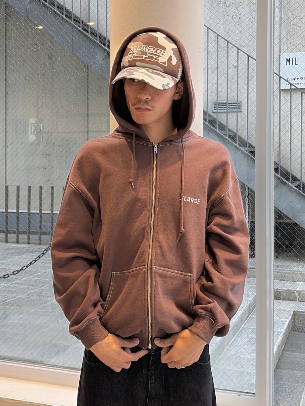 ブラウン系のパーカー、ブルー系のデニムパンツ、ブラック系のキャップを着用したメンズの秋コーディネートの9枚目の写真