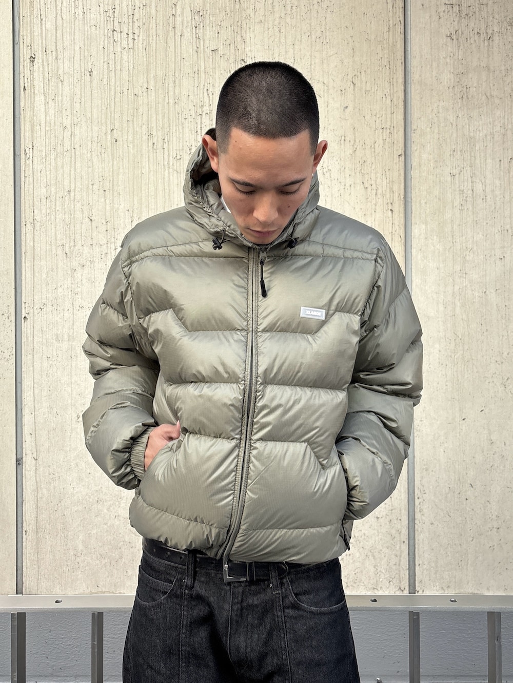 グリーン系のダウンジャケット/コート、ブラック系のデニムパンツを着用したメンズの秋コーディネートの6枚目の写真