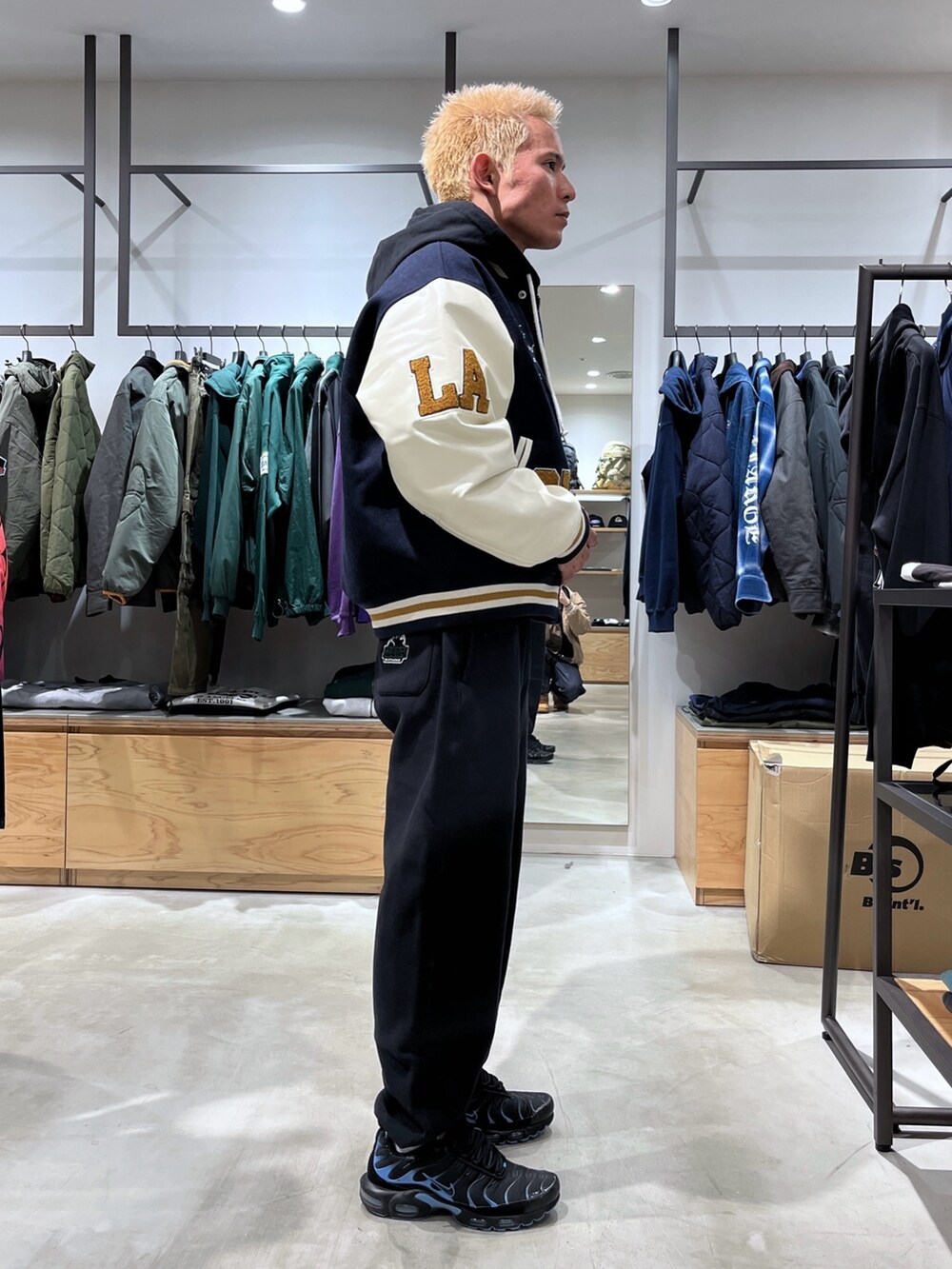 ブルー系のスタジャン、ブラック系のスウェットパンツ、ブラック系のパーカーを着用したメンズの秋コーディネートの3枚目の写真