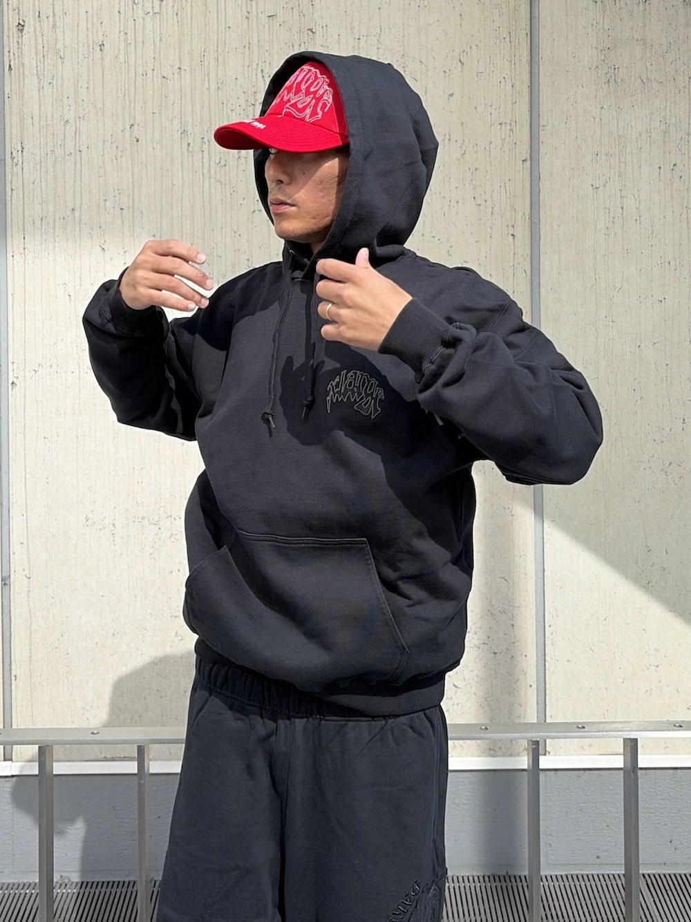 ブラック系のパーカー、ブラック系のその他パンツ、レッド系のキャップを着用したメンズの夏コーディネートの8枚目の写真