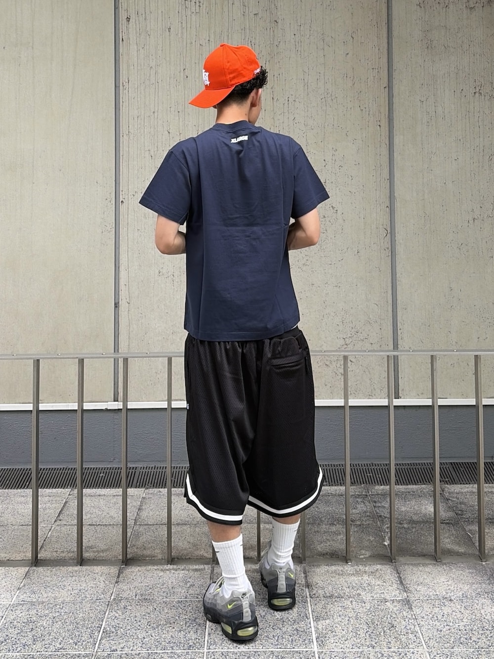 ブラック系のその他パンツ、ブルー系のTシャツ/カットソー、オレンジ系のキャップを着用したメンズの夏コーディネートの5枚目の写真