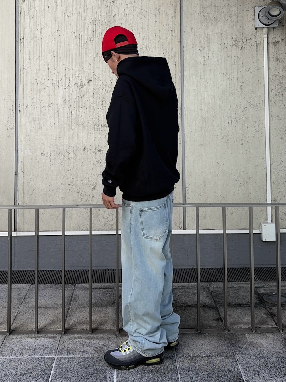 ブラック系のパーカー、ブルー系のデニムパンツ、レッド系のキャップを着用したメンズの秋コーディネートの3枚目の写真