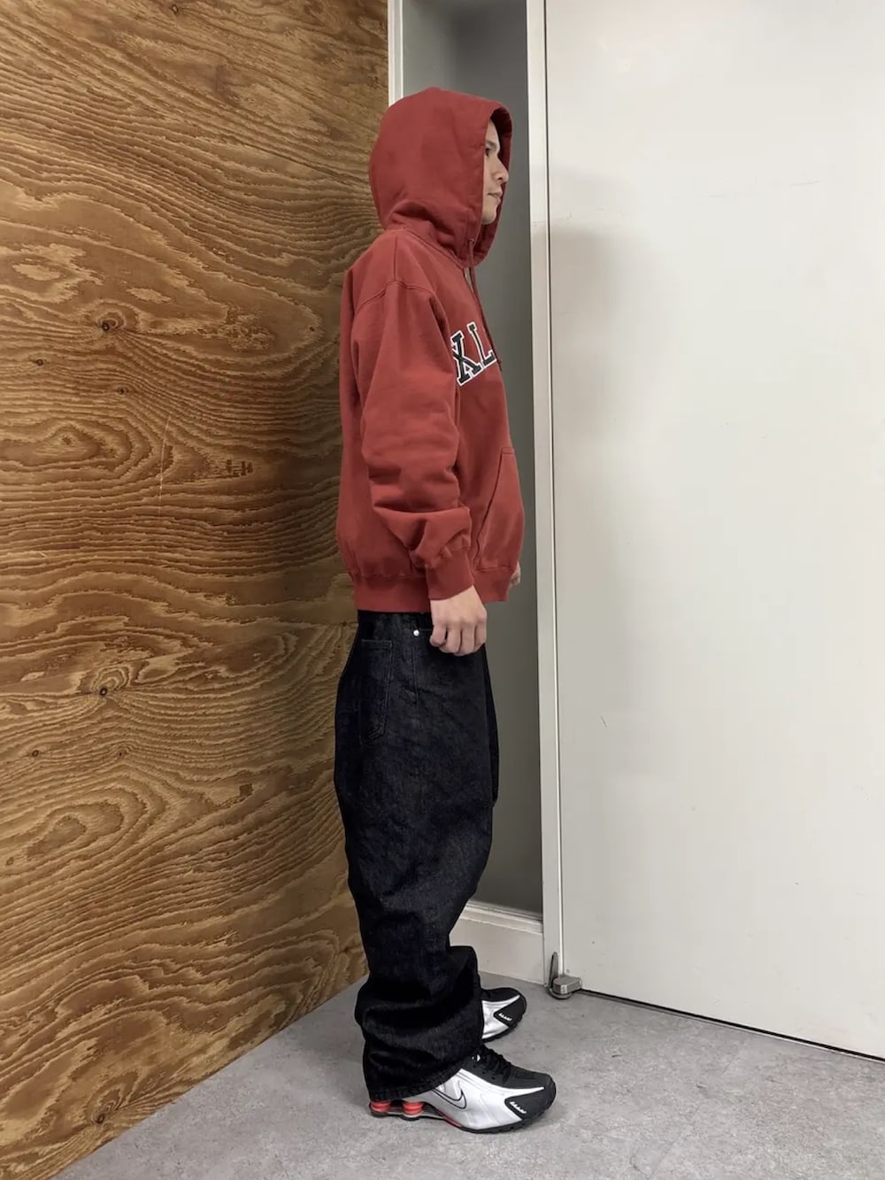 レッド系のパーカー、ブラック系のデニムパンツを着用したメンズの冬コーディネートの4枚目の写真