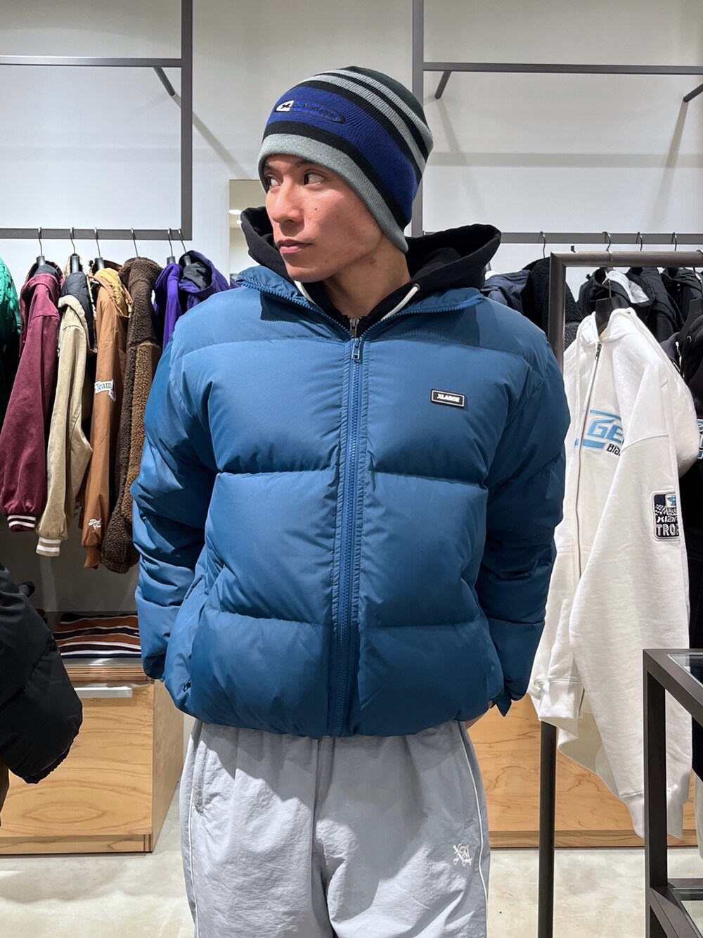 ブルー系のダウンジャケット/コート、グレー系のその他パンツ、ブラック系のニットキャップ/ビーニーを着用したメンズの秋コーディネートの7枚目の写真