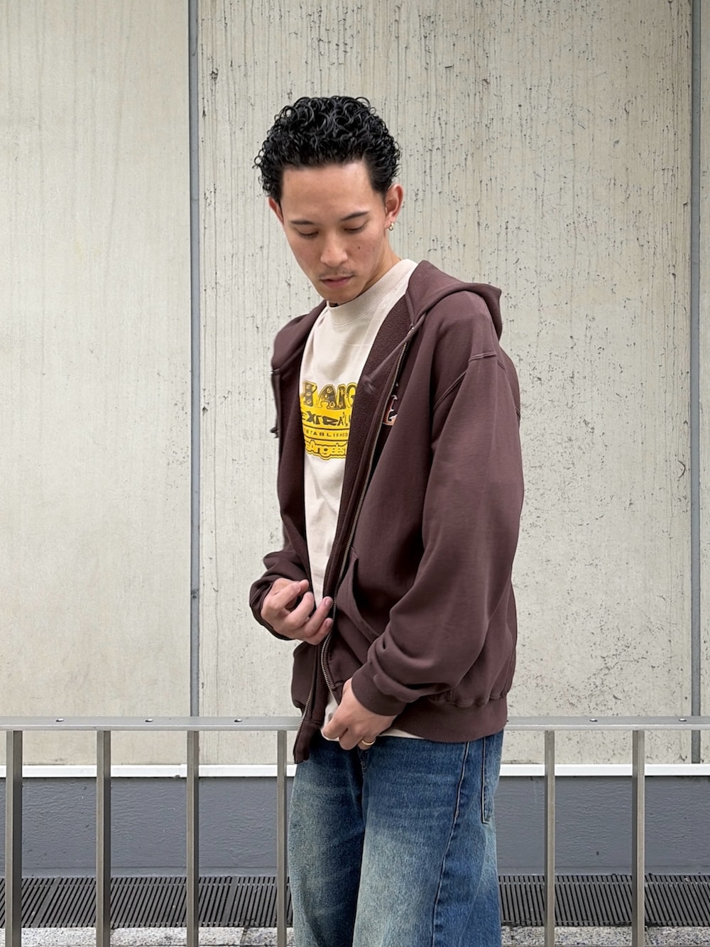 ベージュ系のTシャツ/カットソー、ブラウン系のパーカー、ブルー系のデニムパンツを着用したメンズの春コーディネートの7枚目の写真