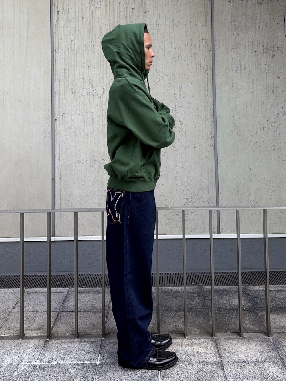 グリーン系のパーカー、ブルー系のデニムパンツを着用したメンズの夏コーディネートの4枚目の写真