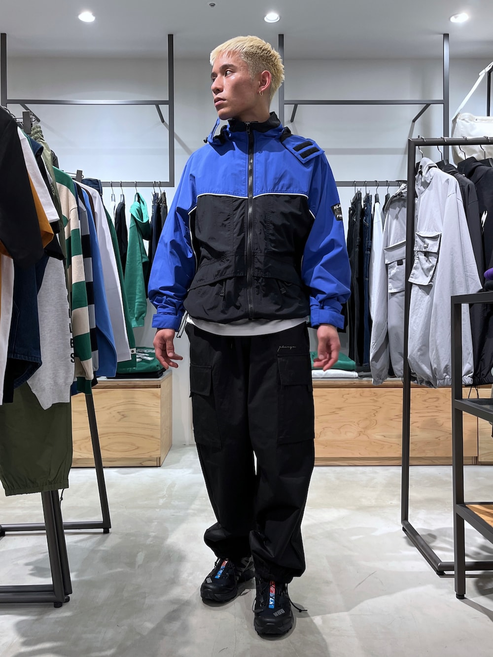 ブルー系のナイロンジャケット、ブラック系のカーゴパンツを着用したメンズの春コーディネートの2枚目の写真