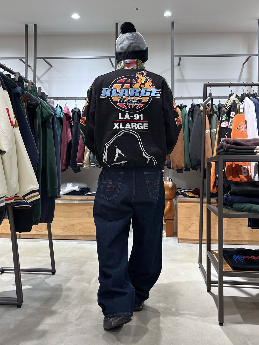 ブラック系のブルゾン、ブルー系のデニムパンツ、グレー系のニットキャップ/ビーニーを着用したメンズの秋コーディネートの5枚目の写真