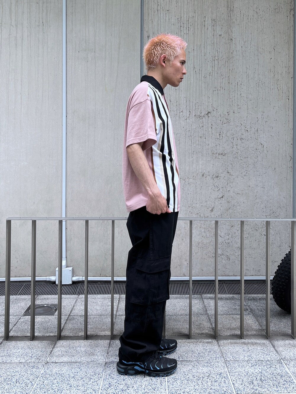 ピンク系のポロシャツ、ブラック系のカーゴパンツを着用したメンズの春コーディネートの3枚目の写真