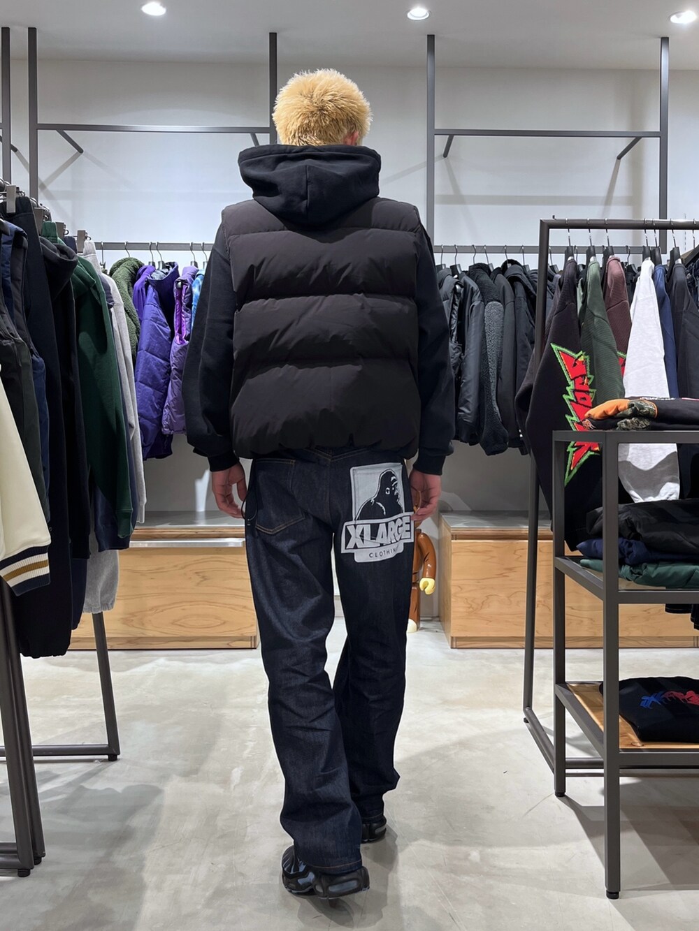 ブラック系のダウンベスト、ブラック系のパーカー、ブルー系のデニムパンツを着用したメンズの秋コーディネートの4枚目の写真