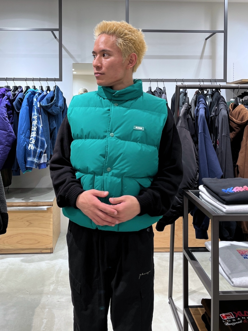 ブラック系のニット/セーター、グリーン系のダウンベスト、ブラック系のカーゴパンツを着用したメンズの秋コーディネートの6枚目の写真