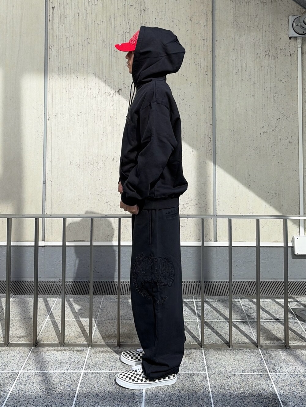 ブラック系のパーカー、ブラック系のその他パンツ、レッド系のキャップを着用したメンズの夏コーディネートの3枚目の写真