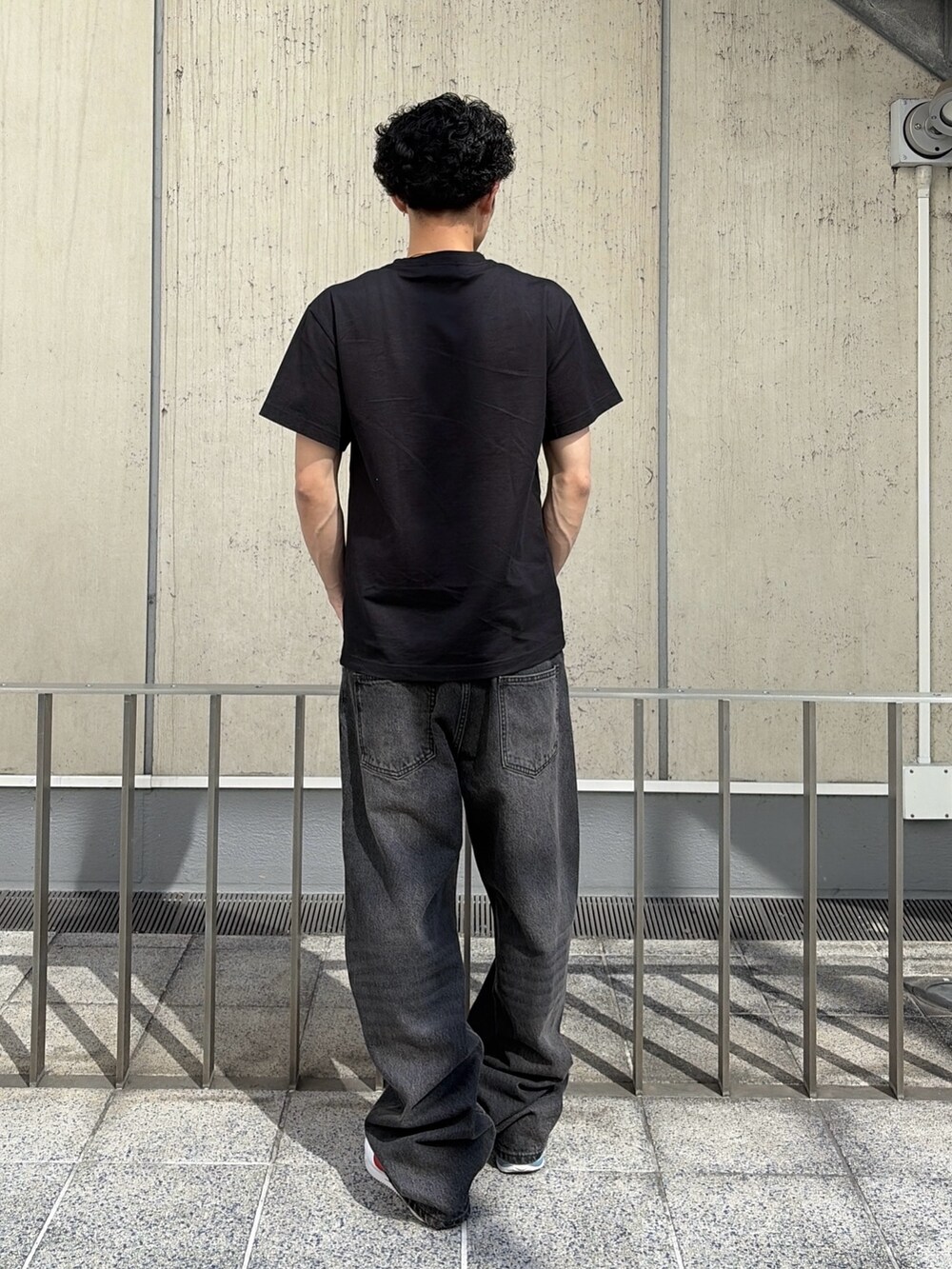ブラック系のTシャツ/カットソー、ブルー系のデニムパンツを着用したメンズの春コーディネートの5枚目の写真