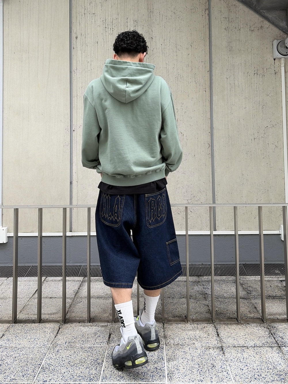 ピンク系のパーカー、ブルー系のデニムパンツを着用したメンズの春コーディネートの4枚目の写真