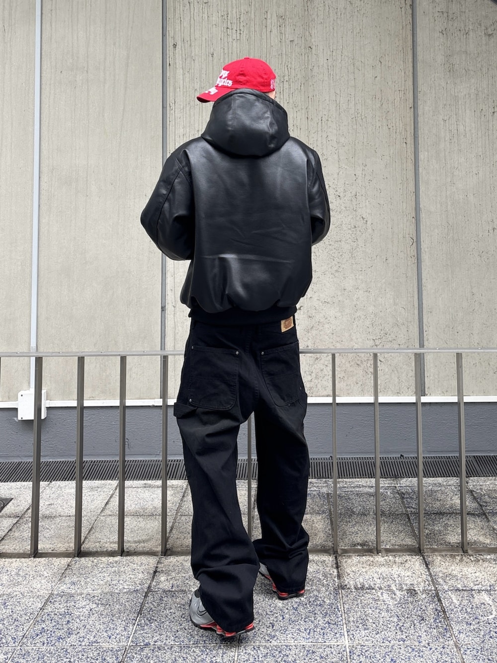 ブラック系のその他アウター、ブラウン系のその他パンツ、レッド系のキャップを着用したメンズの冬コーディネートの4枚目の写真