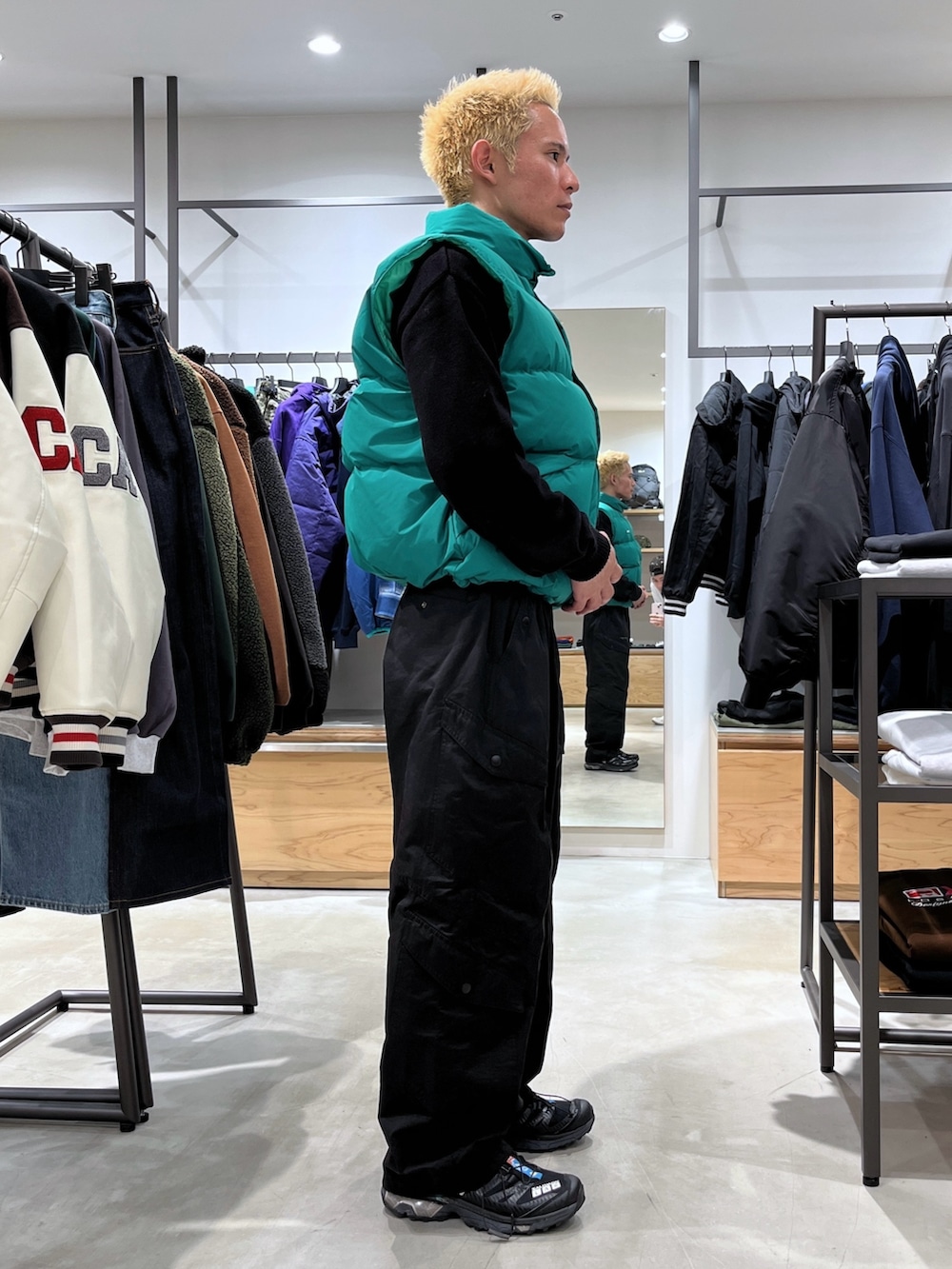 ブラック系のニット/セーター、グリーン系のダウンベスト、ブラック系のカーゴパンツを着用したメンズの秋コーディネートの3枚目の写真