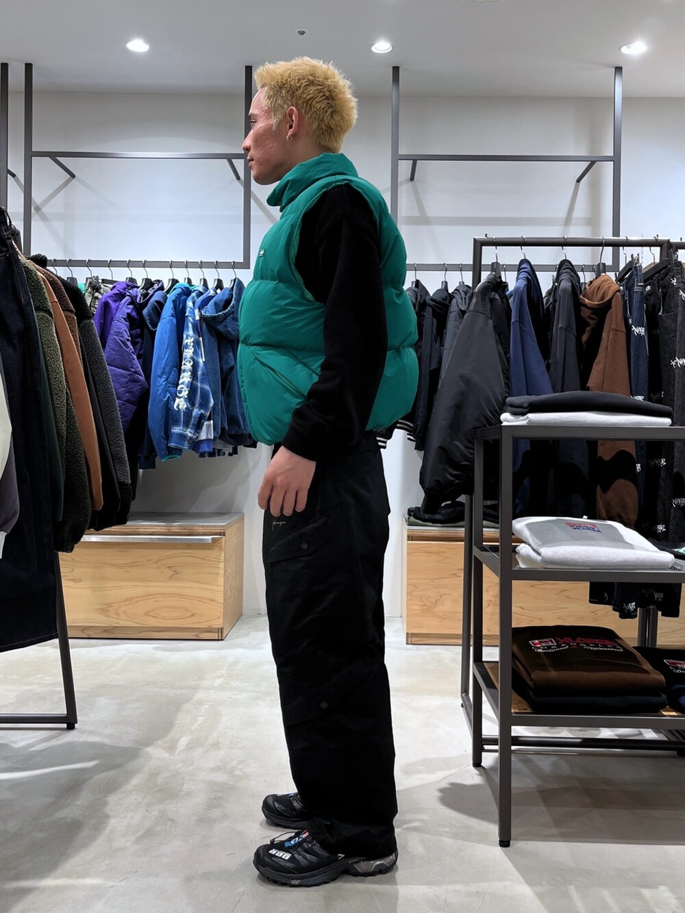 ブラック系のニット/セーター、グリーン系のダウンベスト、ブラック系のカーゴパンツを着用したメンズの秋コーディネートの2枚目の写真