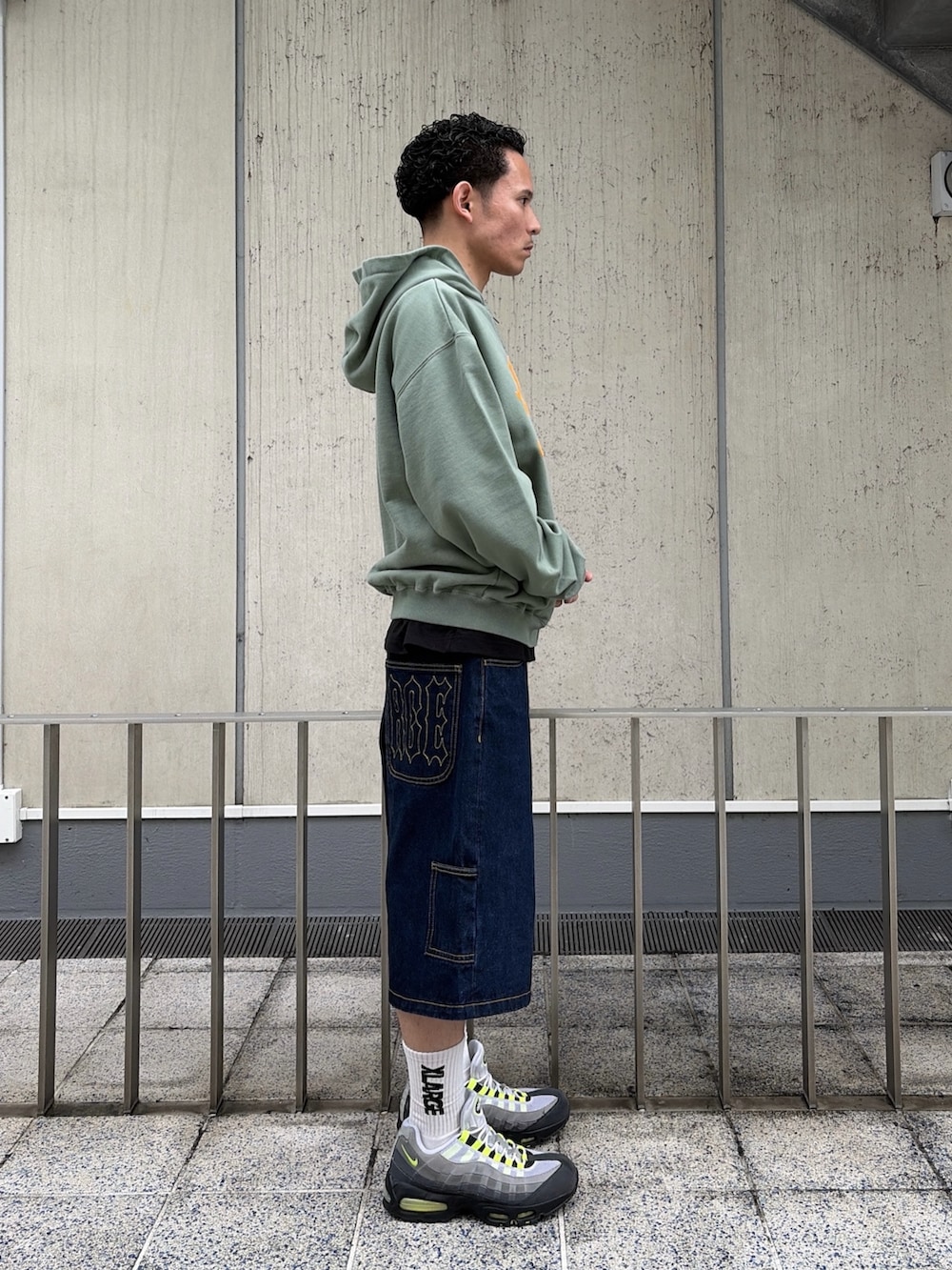 ピンク系のパーカー、ブルー系のデニムパンツを着用したメンズの春コーディネートの3枚目の写真