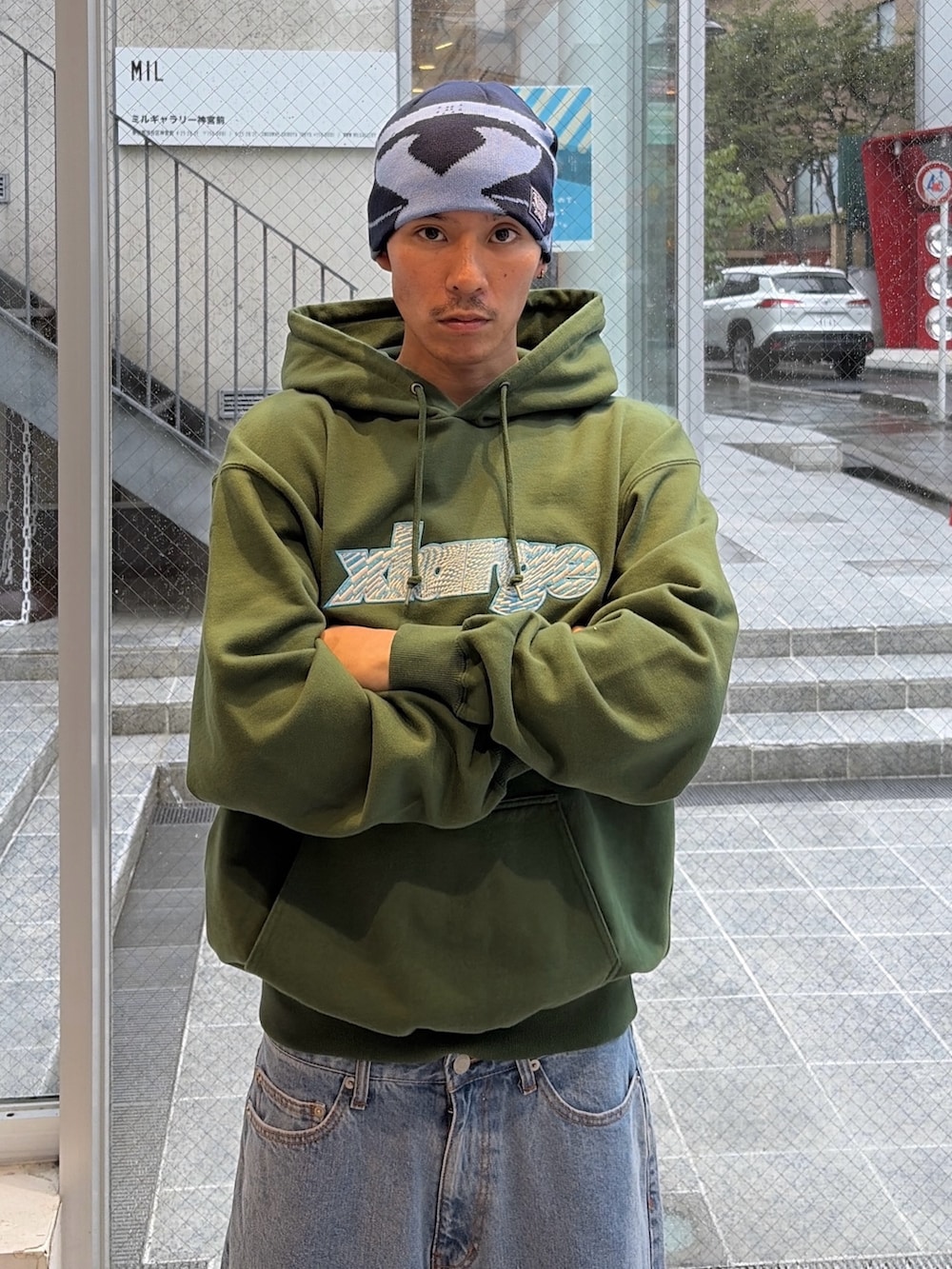 グリーン系のパーカー、グリーン系のデニムパンツ、ブルー系のキャップを着用したメンズの秋コーディネートの5枚目の写真