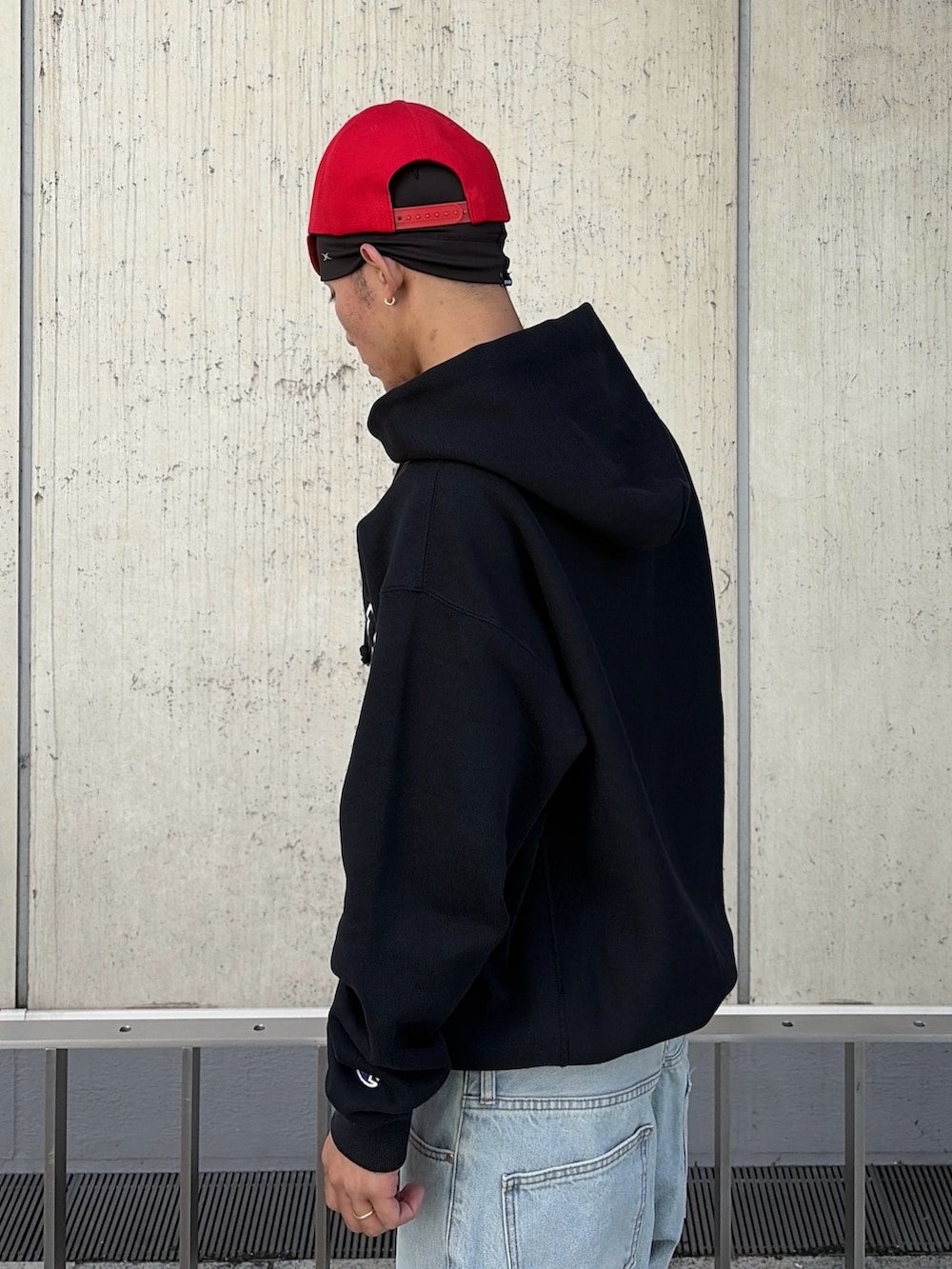 ブラック系のパーカー、ブルー系のデニムパンツ、レッド系のキャップを着用したメンズの秋コーディネートの8枚目の写真