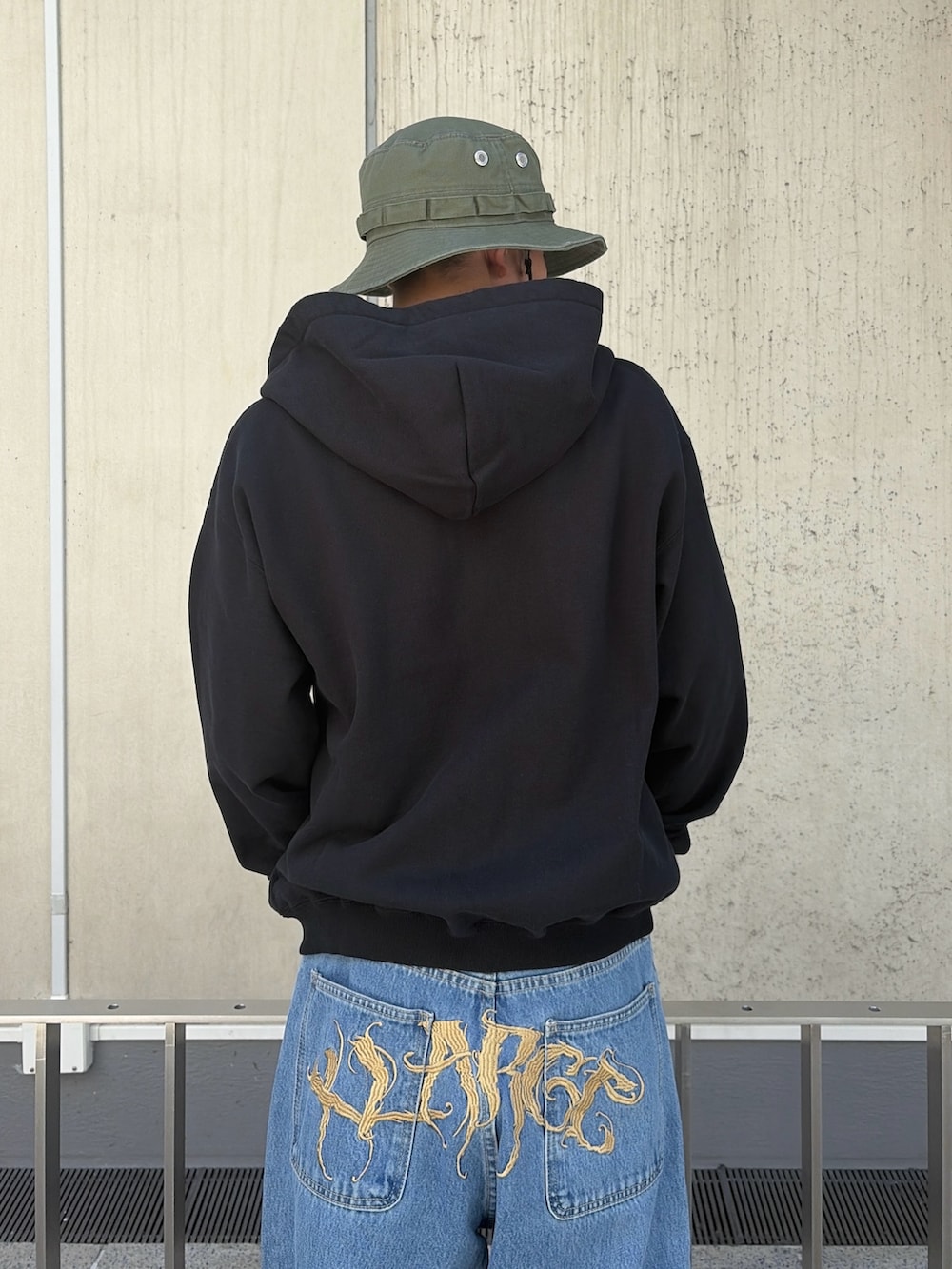 ピンク系のパーカー、ブルー系のデニムパンツ、ブラック系のハットを着用したメンズの春コーディネートの6枚目の写真