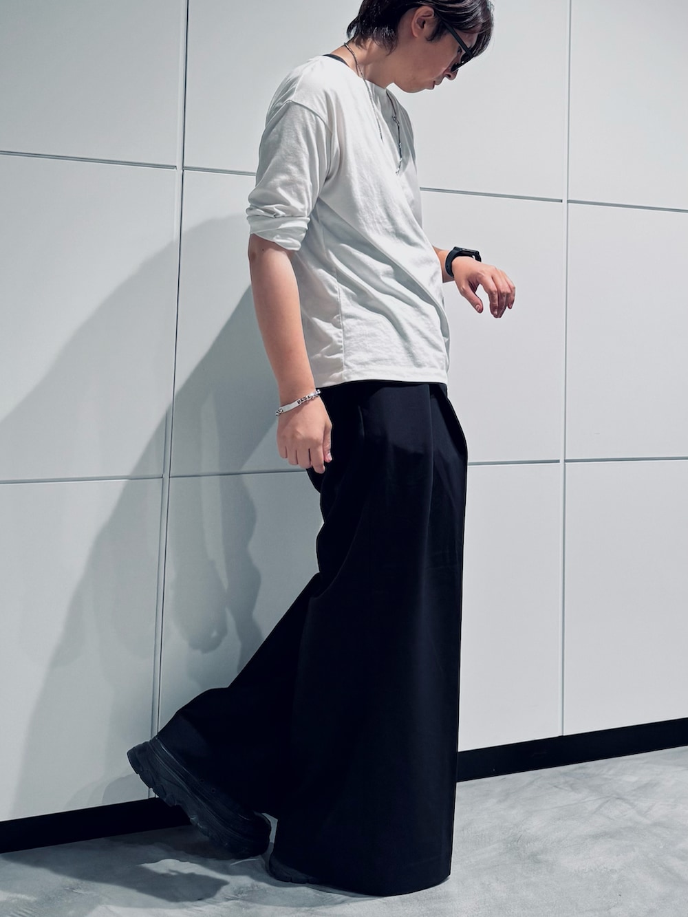 ブラック系のスニーカー、ホワイト系のTシャツ/カットソー、ブラック系のスラックスを着用したメンズの夏コーディネートの2枚目の写真